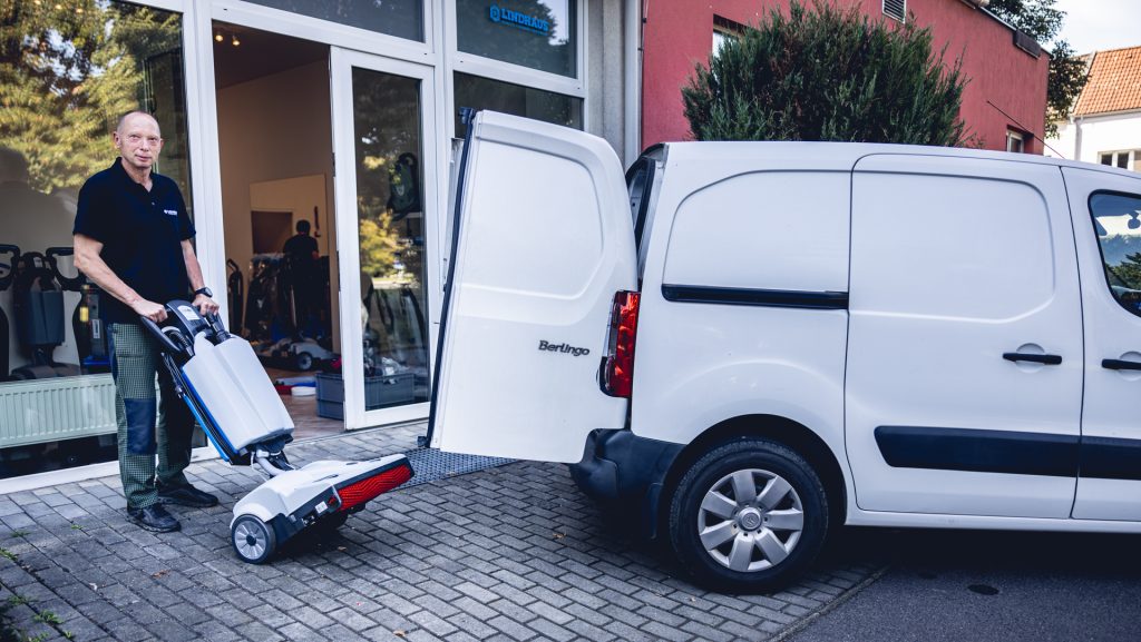 Technik nakladá podlahový umývací stroj LINDHAUS LW46 do úžitkového automobilu pred showroomom LINDHAUS